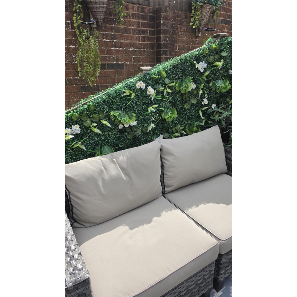 Customer display of mixed foliage and daisy panels behind a sofa