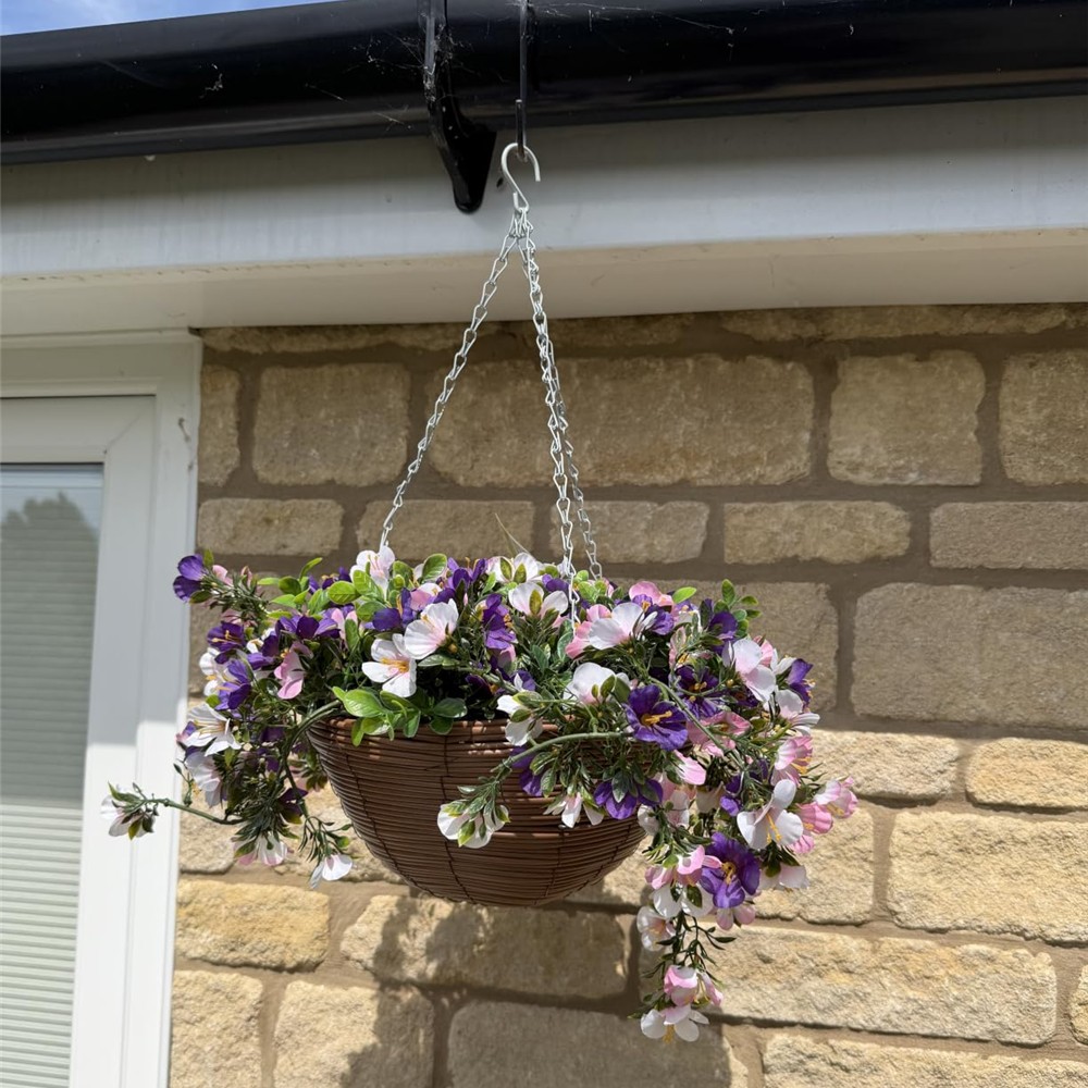 Customer photograph of pink, purple and white artificial petunias hanging against a stone wall