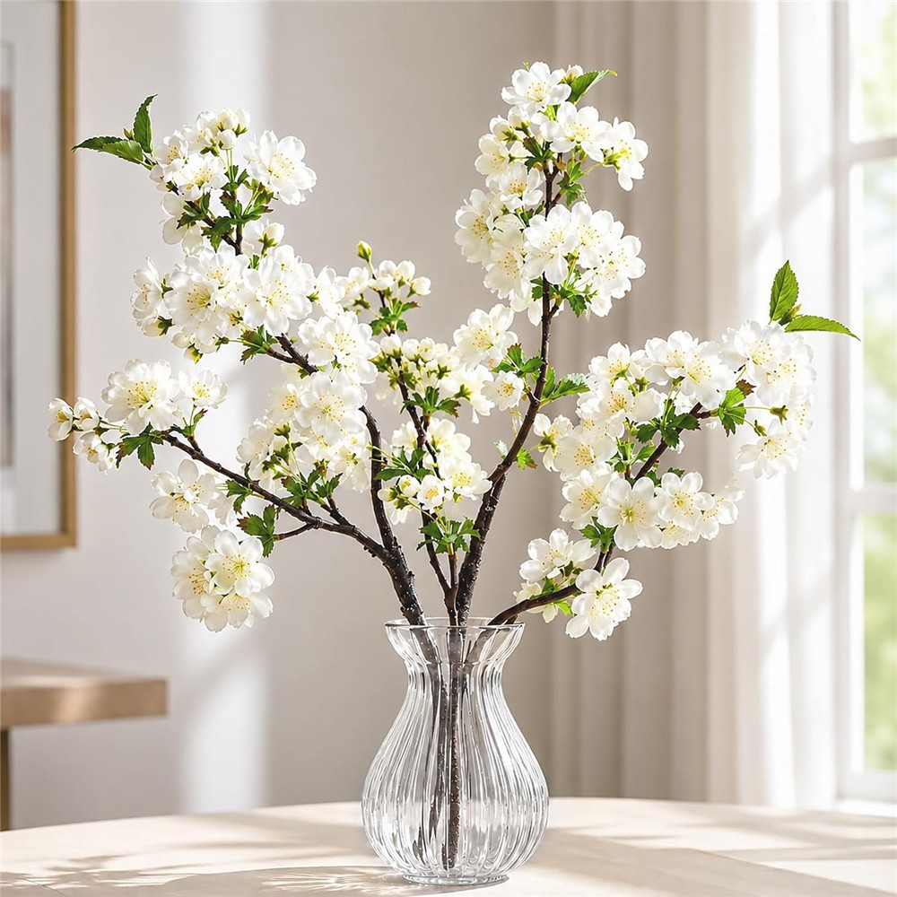 White artificial cherry blossom branches shown in a clear styling vase